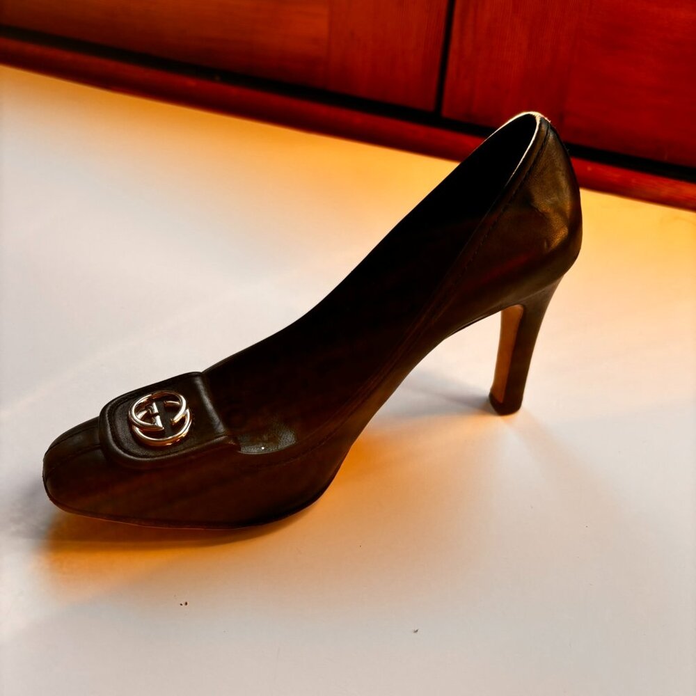 Elegant GUCCI high heel pumps in black leather. Prominent GUCCI logo in gold. 37